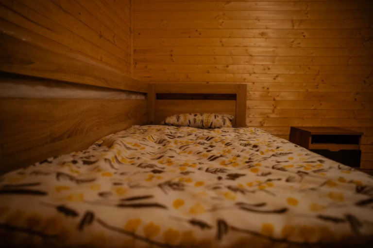 Ustlaná postel v chatce, večerní klid po pobytu ve tmě